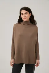 Polera de punto color marrón, de diseño holgado con mangas murciélago y cuello alto vuelto.