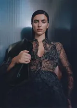 Camisa de organza semitransparente con estampado de serpiente en tonos marrones y verdes. Tiene corte recto, cuello camisero, dos bolsillos de parche en el frente y cierre de botones.