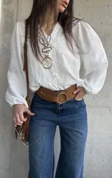 Camisa blanca de manga larga abullonada, con delicados bordados frontales y cierre con botones.