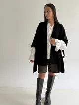 Ruana de tejido de punto trenzado en color crudo, con diseño abierto, corte holgado y mangas amplias tipo kimono.