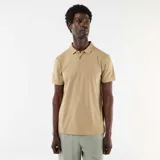 Remera polo color beige de manga corta, confeccionada en tejido texturizado tipo nido de abeja, con cuello camisero y cierre frontal de botones.