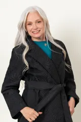 Trench negro capitoneado con bordado floral, corte clásico, cuello solapa, cierre cruzado con broches, lazo para ajustar en la cintura y bolsillos laterales.