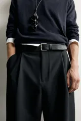 Cinturón de cuero negro con efecto vintage, costuras laterales a tono y hebilla metálica rectangular con acabado plateado envejecido.