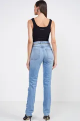 Pantalón de jean celeste con corte recto, tiro alto, detalles de roturas en las rodillas y cadena dorada decorativa en la cintura.