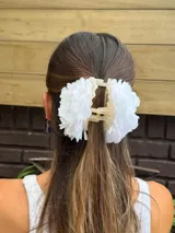Pinza para el pelo con diseño de flores blancas grandes estilo clavel, con mecanismo de agarre tipo clip en tono beige.