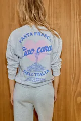 Sudadera de cuello redondo y manga larga, confeccionada en tejido gris melange. Presenta un diseño estampado en el pecho con un corazón y la frase 'Pasta fresca Ciao cara! Dell'Italia'. Cuenta con puños y ruedo acanalados.
