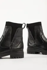 Bota tipo chelsea de caña media en color beige, con suela track dentada y paneles laterales elásticos acanalados.