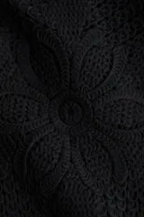 Top negro de manga corta en tejido de punto estilo crochet, con escote redondo, hombreras y cierre oculto en la espalda.