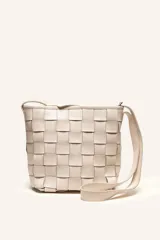 Cartera tipo morral de cuero color beige, con diseño trenzado artesanal, correa larga regulable y cierre superior.