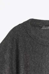 Jersey de punto liso con cuello redondo y mangas cortas anchas. Presenta acabados en rib en el cuello, puños y bajo.