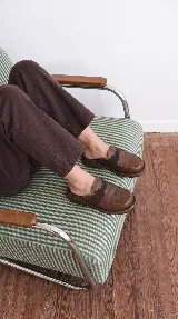 Zueco de cuero marrón, con diseño inspirado en mocasines, tira elástica en el empeine y suela plana confortable.
