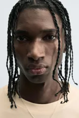 Camiseta de algodón de corte relajado, color beige claro, con cuello redondo y manga corta. Presenta un estampado central de garabatos negros con texto en mayúsculas que dice "TAKE RIGHT STEP FIND A RIGHT CORD".