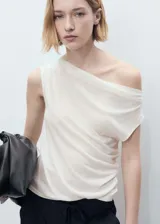 Top asimétrico de color blanco con cuello drapeado y diseño entallado. Presenta un corte de un solo hombro, dejando el otro al descubierto.