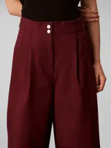 Pantalón chino de pierna ancha y talle alto Calvin Klein, color bordó, con cierre de doble botón y cremallera, bolsillos laterales y detalles de costura frontal.