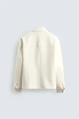 Sobrecamisa marrón de corte boxy fit en tejido compacto, con cuello solapa, manga larga con puños abotonados, bolsillos frontales de parche y cierre central de botones.