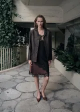 Blazer de cuero ovino color marrón oscuro, con diseño de corte recto, solapas clásicas y cierre frontal con botones a tono.