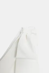 Vestido corto blanco de escote asimétrico con un solo tirante ancho que forma un lazo sobre el hombro. Presenta frunces laterales y cierre oculto.