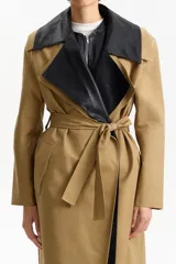 Gabardina larga color camel de silueta recta, con cuello de solapa ancha en contraste de piel sintética negra. Posee mangas largas, bolsillos laterales con solapa y cinturón a juego para ajustar a la cintura.