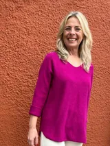Sweater de hilo color fucsia, de corte holgado, con escote en V y mangas largas con vuelta.