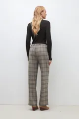 Pantalón largo de corte recto con estampado de cuadros escoceses en tonos beige, marrón y negro. Tiene cintura elástica con cordón ajustable.