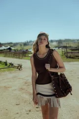 Minifalda color crema de cuero ovino con flecos y detalles en cuero marrón. Cierre frontal con cremallera. Estilo country.