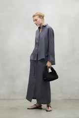 Camisa de corte holgado confeccionada en lino, con cuello clásico, cierre frontal de botones y mangas largas con puños sencillos.