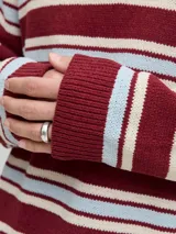 Polo tejido de manga larga con fit relajado, color rojo tibetano con rayas horizontales en blanco y celeste. Presenta medio cierre de botones.