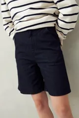 Bermuda negra de tiro medio con silueta recta y largo a la altura de la rodilla. Presenta bolsillos laterales y traseros, y costuras visibles.