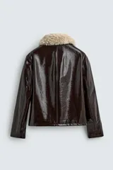 Cazadora de corte regular fit confeccionada en tejido efecto piel con acabado vinilo brillante en color marrón oscuro. Presenta cuello de solapa con tejido de borreguillo a contraste, cierre frontal de cremallera y bolsillos laterales de vivo.