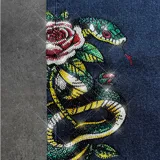 Pantalón de jean color azul oscuro con corte baggy, presenta estampados gráficos estilo tatuaje en ambas piernas.