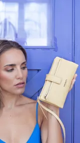 Billetera Lincoln's de mujer en color negro, confeccionada en símil cuero con textura granulada. Presenta un diseño rectangular con cierre de broche, bolsillo frontal con cierre metálico, correa de mano extraíble y logo de la marca grabado en el frente.