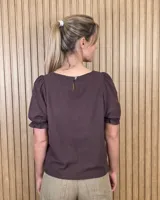Blusa blanca de corte recto con escote a la base y mangas cortas abullonadas con terminación fruncida.