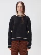 Sweater de punto con diseño de ochos en color verde, cuello redondo con detalle de franja en contraste, y apliques de rombos en las mangas. Presenta un bordado con la letra M en el pecho.