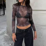 Remera manga larga de microtul transparente elastizado, con estampado abstracto en tonos grises y negros, cuello redondo y terminaciones con ondas en los bordes.