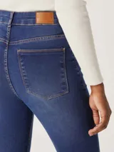 Pantalón de jean azul oscuro, tiro alto, corte super skinny y acabado liso.