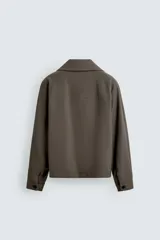 Sobrecamisa relaxed fit de Zara confeccionada en tejido negro con estructura diagonal. Presenta cuello subido, manga larga, bolsillos de vivo en la cadera y cierre frontal con cremallera.