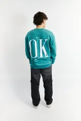 Buzo oversize verde inglés con estampa frontal con la frase "It's OK, don't worry" en color blanco.