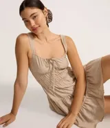 Vestido corto de silueta evasé color celeste, con escote recto y detalle de lazo en el centro. Posee breteles medianos, cintura elástica fruncida y falda con volados escalonados.