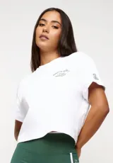 Remera blanca de algodón con corte crop, mangas cortas y estampado frontal con texto y logo en color gris.