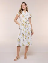Vestido camisero midi de silueta evasé, confeccionado en tejido liviano blanco con estampado floral amarillo y rayas celestes. Cuenta con cuello solapa en V, cartera con botones frontales, mangas cortas japonesas y cintura definida con lazo ajustable a juego.