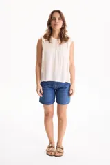 Blusa de viscosa negra sin mangas, con diseño fluido, cuello redondo y detalles de tablas verticales en el pecho con terminaciones de encaje en las sisas.