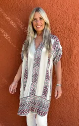 Camisa de seda con fondo crudo y estampado floral multicolor. Presenta cuello camisero, cierre frontal con botones y mangas cortas con diseño holgado.