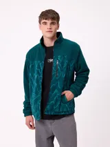 Campera reversible con cuello alto y cierre frontal. Un lado presenta tejido de polar con estampado geométrico en tonos verdes y bolsillo con cierre en el pecho, mientras que el otro lado es de nylon. Cuenta con puños elásticos y bolsillos laterales.