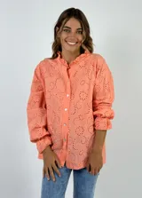 Camisa azul con bordado calado, cuello mao con volantes y mangas largas con puños elásticos.