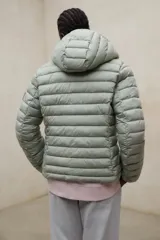 Campera puffer con capucha, color verde, diseño acolchado con costuras horizontales y cierre frontal.