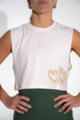 Musculosa crop blanca de algodón elastizado, sin mangas, con cuello redondo y diseño estampado en tono dorado.