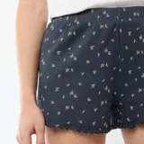 Pantalón corto de pijama azul marino de algodón con estampado de pequeñas flores blancas y detalles ondulados en el borde inferior.