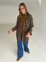 Sobrecamisa de lana con estampado de cuadros en tonos tierra, corte oversize, cuello camisero, cierre frontal de botones y bolsillos delanteros con solapa.