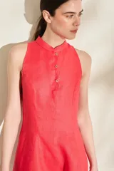 Vestido corto de lino color rojo, sin mangas, con cuello mao y cierre frontal de botones. Presenta falda con vuelo gracias a sus godettes.