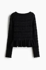 Top negro de manga larga en tejido fruncido con escote bote y detalles de volados en el diseño, corte entallado y peplum.
